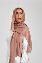 Woman wearing a white dress and a dusty rose hijab on a white background