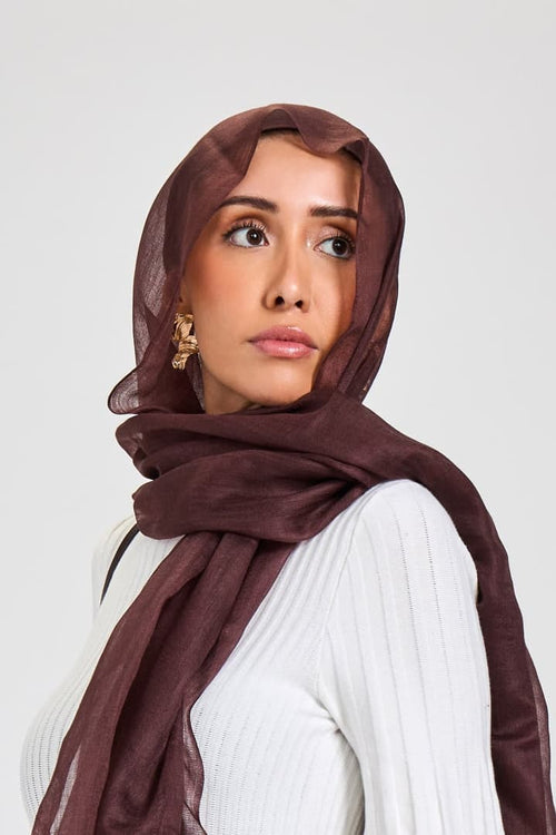 Woman wearing a white dress and brown hijab on a white background